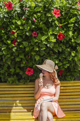 Frau mit Buch sitzt auf einer Bank und isst Eis, Frigiliana, Malaga, Spanien - LJF00683