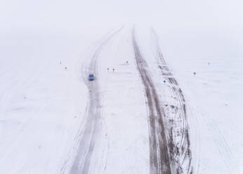 Luftaufnahme eines Autos auf einer vereisten Straße im Schneesturm in Rohukula, Estland. - AAEF02519