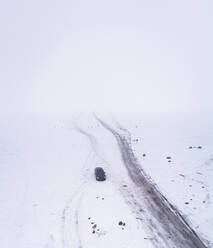 Aerial view of a car driving on a frozen road in the Blizzard in Rohukula, Estonia. - AAEF02520