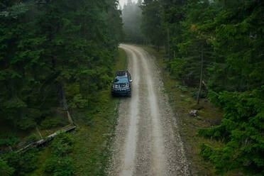 Luftaufnahme eines schwarzen Autos, das durch den Wald in Forby auf der Insel Vormsi, Estland, fährt - AAEF02529