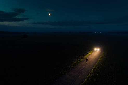 Luftaufnahme eines Mannes auf der Straße bei Nacht und abnehmendem Mond, Estland - AAEF02610