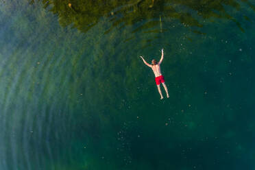 Aerial view of man floating on water at Sinijärv lake in Estonia. - AAEF02627