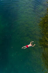 Aerial view of man floating on water at Sinijärv lake in Estonia. - AAEF02628