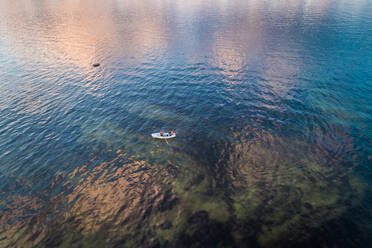 Luftaufnahme von zwei Personen in einem kleinen Holzboot auf der bunten Ostsee bei Sonnenuntergang. - AAEF02683