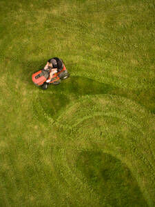 Luftaufnahme eines Mannes, der den Rasen mäht und dabei Formen schafft. - AAEF02690