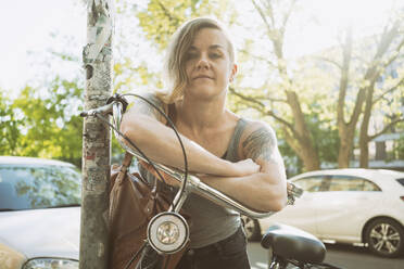 Portrait of tattooed woman with a bike in the city - TAMF02053