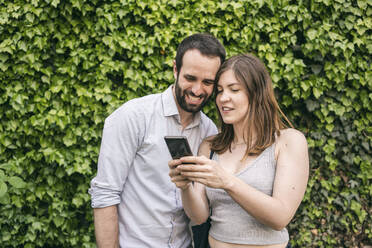 Glückliches junges Paar teilt sich ein Mobiltelefon - TAMF02095