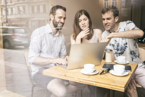 Eine Gruppe von Freunden sitzt mit einem Laptop in einem Café zusammen, lizenzfreies Stockfoto