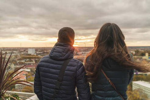 Paar beobachtet den Sonnenuntergang über der Stadt von einer Aussichtsterrasse aus, Tallinn, Estland - TAMF02138