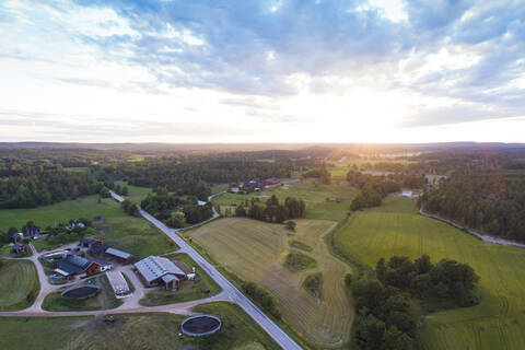 Luftaufnahme von Feldern und Straße vor Sonnenuntergang im Sommer, Vaestervik, Schweden, lizenzfreies Stockfoto