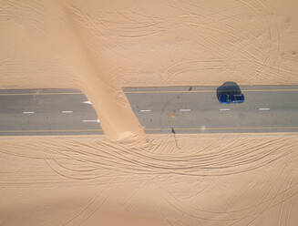 Luftaufnahme eines Autos auf einer mit Sand bedeckten Straße in der Wüste von Dubai, V.A.E. - AAEF02774