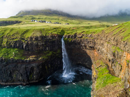 Luftaufnahme des Wasserfalls Múlafossur in der Nähe eines kleinen Dorfes, Färöer-Insel. - AAEF02955