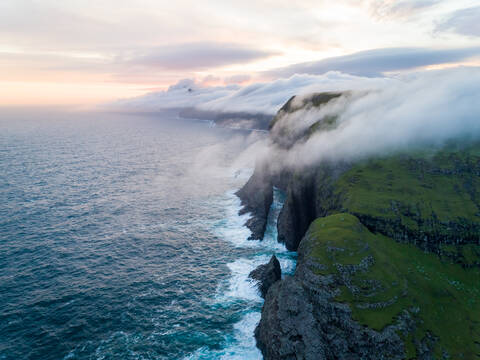 Luftaufnahme einer Klippe im Nordatlantik während des Sonnenuntergangs auf den Färöer-Inseln., lizenzfreies Stockfoto