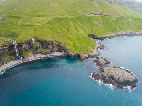 Luftaufnahme eines kleinen Wasserfalls, der im Nordatlantik endet, Färöer-Insel., lizenzfreies Stockfoto