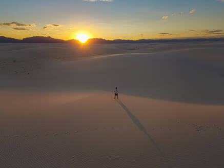 Luftaufnahme einer Person, die allein in der Mitte des White Sands National Monument bei Sonnenuntergang in Tularosa, USA, steht. - AAEF03014