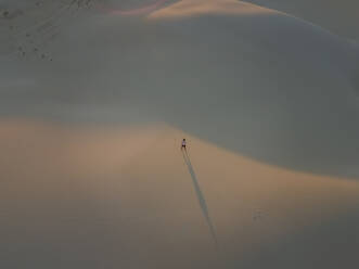 Luftaufnahme einer Person, die allein in der Mitte des White Sands National Monument bei Sonnenuntergang in Tularosa, USA, steht. - AAEF03015