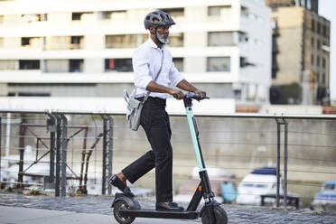 Älterer Geschäftsmann fährt E-Scooter - FMKF05899