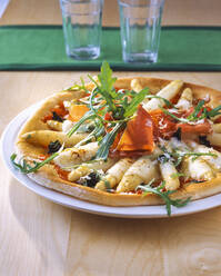 Pizza mit Spargel und Schinken im Teller auf dem Tisch - PPXF00250