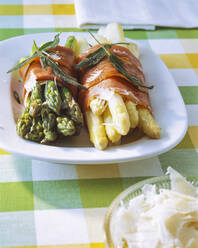 Grüner und weißer Spargel mit Speck umwickelt auf einem Teller - PPXF00255