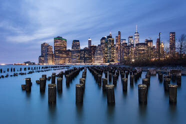 Lower Manhattan skyline with wooden posts from an old pier in the foreground. New York City, New York, United States of America, North America - RHPLF00740
