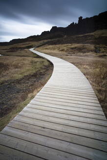 Uferpromenade, die sich zu den schroffen Klippen und dem stürmischen Himmel im Thingvellir-Nationalpark in der Nähe von Reykjavik, Island, Polarregionen, schlängelt - RHPLF00807