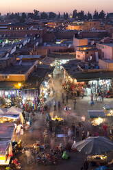 Menschenmassen von Einheimischen und Touristen zwischen den Geschäften und Ständen auf dem Djemaa el Fna bei Sonnenuntergang, Marrakesch, Marokko, Nordafrika, Afrika - RHPLF00817