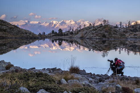 Ein Fotograf betrachtet den Sonnenuntergang über dem Monte Rosa vom Lago Bianco im Naturpark Mont Avic, Aosta-Tal, Italien, Europa - RHPLF00966