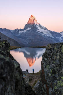 Hikers admire the Matterhorn reflected in the Stellisee at sunrise, Zermatt, Canton of Valais, Pennine Alps, Swiss Alps, Switzerland, Europe - RHPLF00984