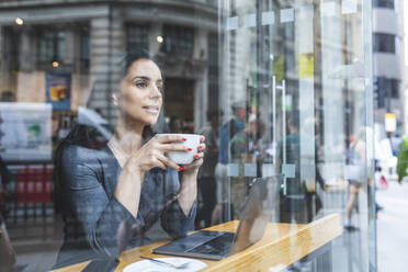 Business woman having a coffee and looking out of the window - WPEF01797