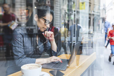 Geschäftsfrau, die in einem Café eine Pause macht und mit einem Laptop arbeitet - WPEF01800