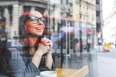 Lächelnde Frau hinter einer Fensterscheibe in einem Cafe - WPEF01802