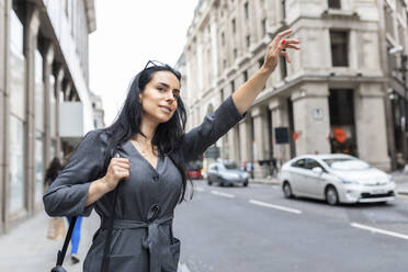 Frau in der Stadt, die ein Taxi ruft, London, UK - WPEF01804