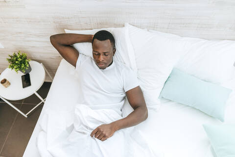 Junger Mann liegt zu Hause im Bett, lizenzfreies Stockfoto