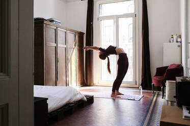 Junge brünette Frau übt Yoga im Studentenwohnheim - IGGF01272