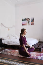 Junge brünette Frau übt Yoga im Studentenwohnheim - IGGF01278
