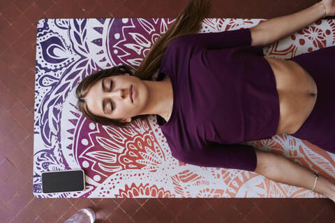 Junge brünette Frau übt Yoga im Studentenwohnheim, lizenzfreies Stockfoto