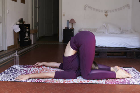 Junge brünette Frau übt Yoga im Studentenwohnheim - IGGF01284