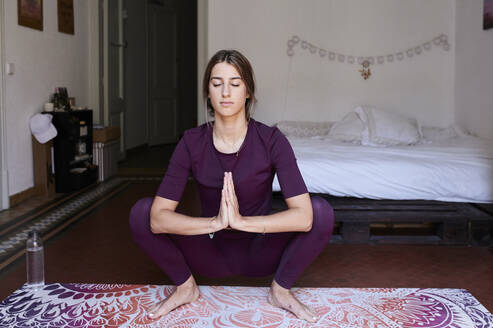 Junge brünette Frau übt Yoga im Studentenwohnheim - IGGF01289