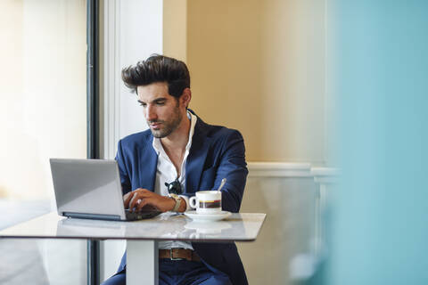 Geschäftsmann mit Laptop in einem städtischen Café, lizenzfreies Stockfoto