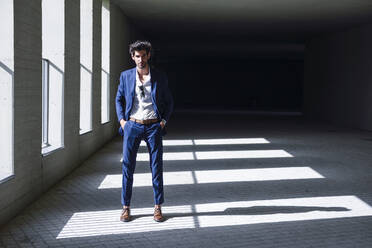 Portrait of confident businessman standing in a passageway - JSMF01217