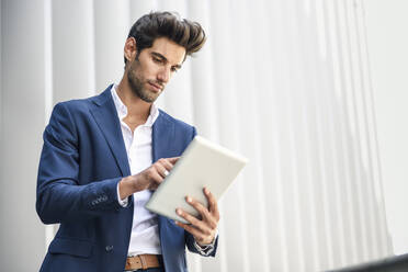 Businessman using tablet outdoors in the city - JSMF01233