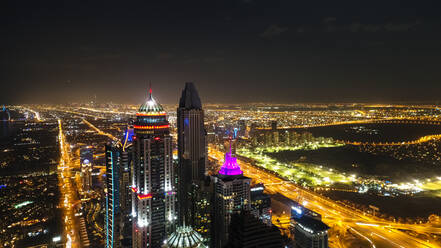 Luftaufnahme von beleuchteten Wolkenkratzern bei Nacht in Dubai, Vereinigte Arabische Emirate. - AAEF03259