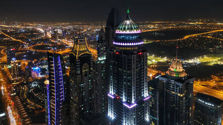 Luftaufnahme von beleuchteten Wolkenkratzern bei Nacht in Dubai, Vereinigte Arabische Emirate. - AAEF03260