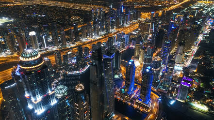 Luftaufnahme von beleuchteten Wolkenkratzern bei Nacht in Dubai, Vereinigte Arabische Emirate. - AAEF03264
