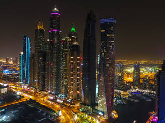 Luftaufnahme von beleuchteten Wolkenkratzern bei Nacht in Dubai, Vereinigte Arabische Emirate. - AAEF03325