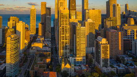 Luftaufnahme von Wolkenkratzern in der herrlichen Skyline der Innenstadt von Chicago, IL in den Vereinigten Staaten, verstärkt durch das warme Sonnenlicht in der Abenddämmerung, mit dem Michigansee im Hintergrund. - AAEF03397