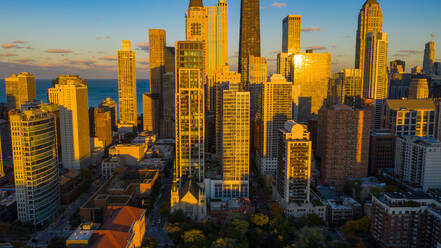 Luftaufnahme von Wolkenkratzern in der herrlichen Skyline der Innenstadt von Chicago, IL in den Vereinigten Staaten, verstärkt durch das warme Sonnenlicht in der Abenddämmerung, mit dem Michigansee im Hintergrund. - AAEF03398