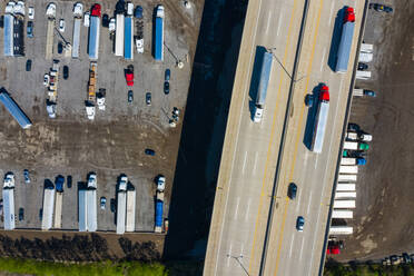 Luftaufnahme von geparkten Sattelschleppern und Autos unter einem Freeway auf einem Parkplatz in Romeoville, IL - USA - AAEF03509