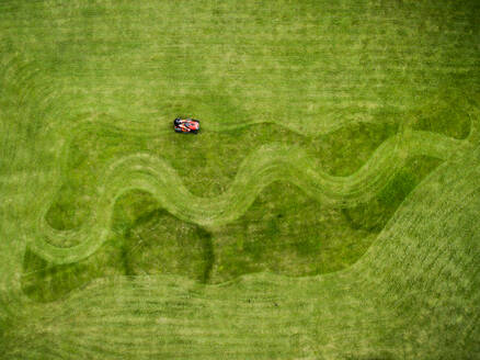 Luftaufnahme eines Mannes auf einem Rasenmäher, der Formen im Gras erzeugt - AAEF03588