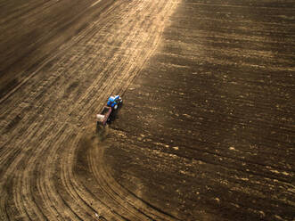 Aerial view of farmer plowing in a farm in the countryside - AAEF03609